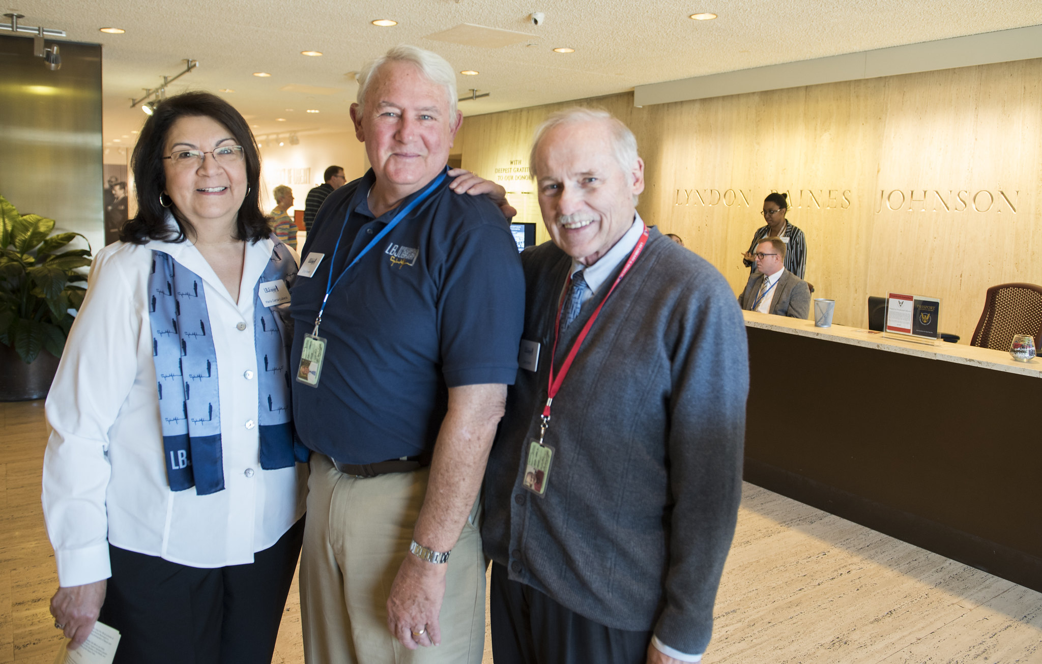 LBJ Library volunteers Maria Garza-Lubeck, Chuck Newell, and Larry Smith greet visitors at the entrance to the LBJ Library.